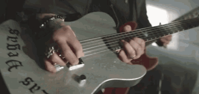 a man is playing a guitar with the word vegas on the neck
