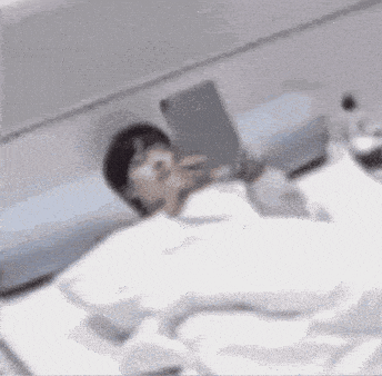 a man is laying in bed reading a book .