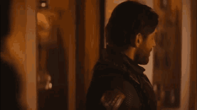 a man with a beard is standing in a dark room with a woman .