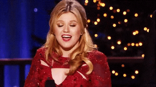 a woman in a red dress is singing into a microphone on a stage .