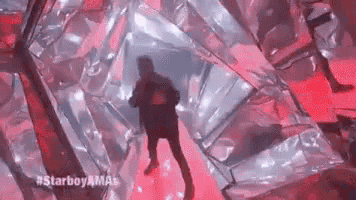 a man is dancing on a stage in a room with a red light behind him .
