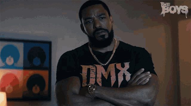 a man with his arms crossed is wearing a tmx t-shirt