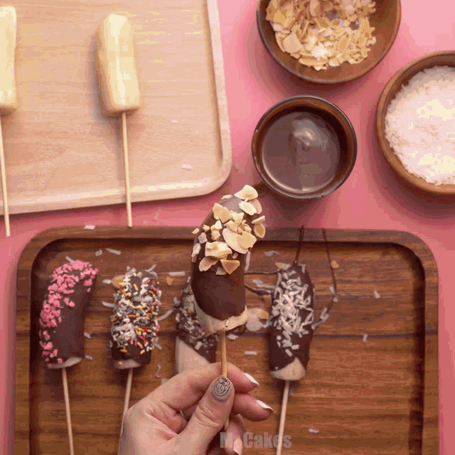 a person is holding a chocolate covered banana on a stick with the words mr. cakes on the bottom