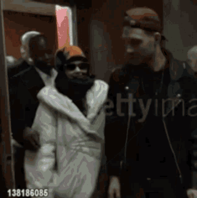 a woman in a fur coat is being escorted by a man in a hat and sunglasses .