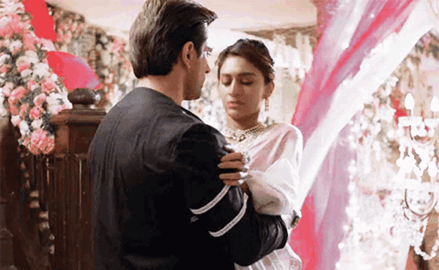 a man and a woman are dancing in a room with flowers