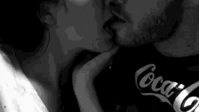 a man and a woman are kissing in a black and white photo .