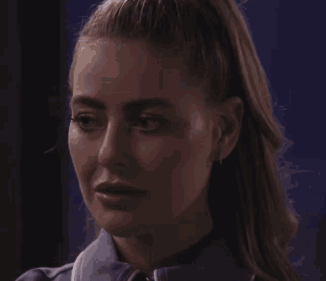 a woman with her hair in a ponytail looks at the camera