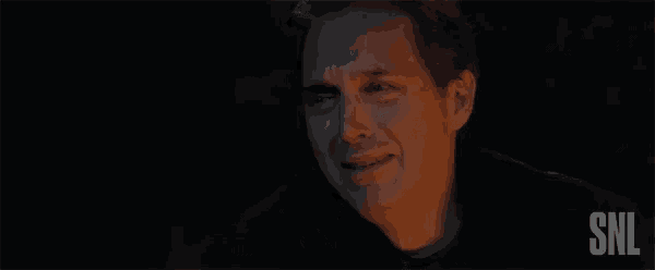 a man is making a face and saying `` no '' in a dark room .