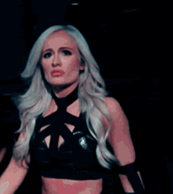 a woman with long blonde hair is wearing a black dress and looking at the camera .