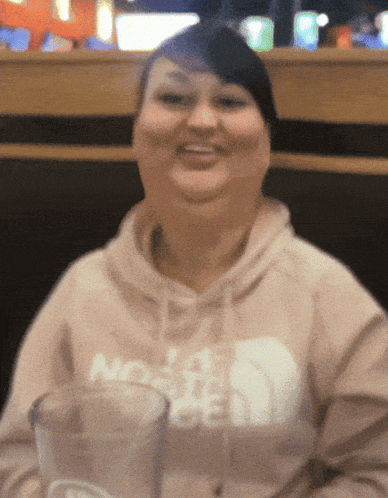 a woman wearing a hoodie that says north face is smiling