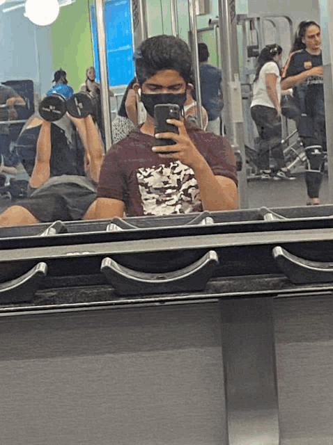 a man wearing a mask takes a selfie in a gym