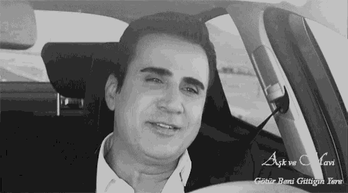 a black and white photo of a man in a car with the words aşk ve mavi written below him