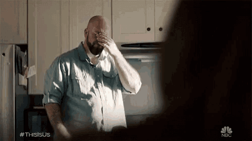 a man covering his face with his hand in a kitchen with a nbc logo in the corner