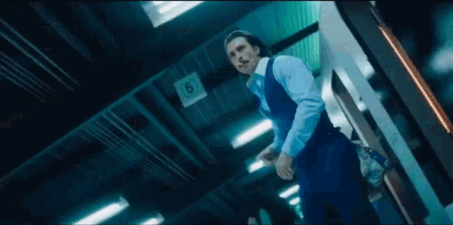 a man in a blue suit is walking down a hallway .