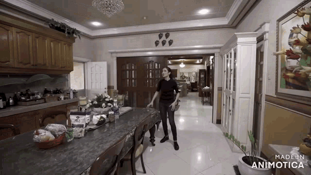 a woman in a black shirt stands in front of a large dining table in a kitchen made in animatica