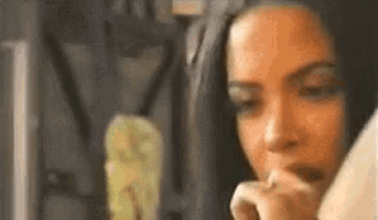 a woman is sitting at a table with her hand on her face and looking at something .