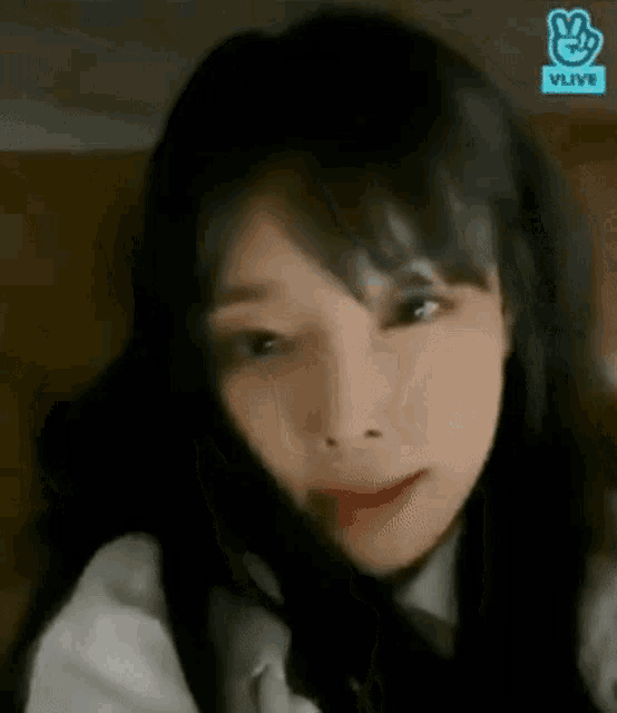 a close up of a woman 's face with long black hair and a white shirt and tie .