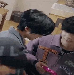a couple of young men are sitting next to each other in a kitchen .