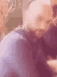 a close up of a bald man with a beard wearing a blue shirt and tie .