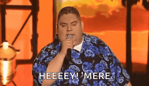 a fat man is singing into a microphone and saying heeeey ! mere .