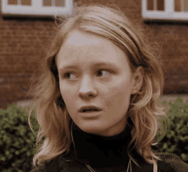 a woman with blonde hair wearing a black turtleneck