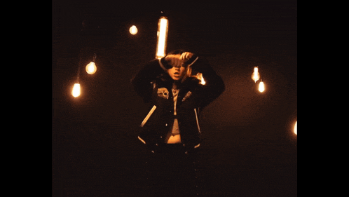a person standing in a dark room surrounded by light bulbs
