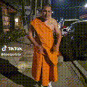 a man in an orange robe is standing on a sidewalk .