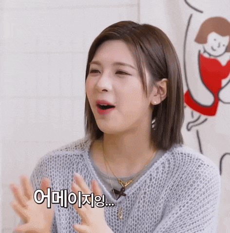 a woman in a grey sweater is making a funny face with her hands in the air