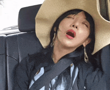 a woman wearing a hat and earrings yawning in a car seat