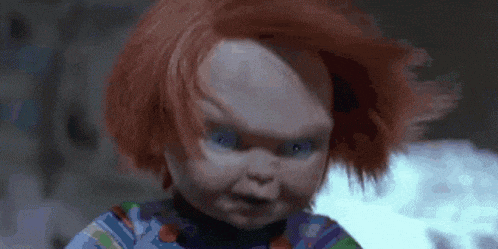 a close up of a creepy doll with red hair and blue eyes .