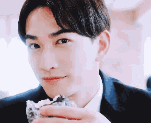 a man in a suit is eating a piece of food