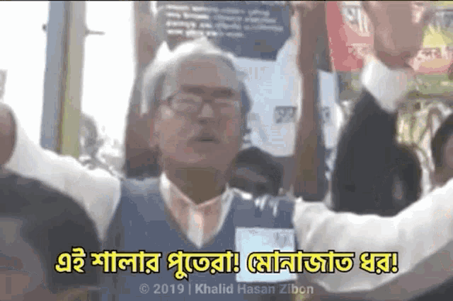 a man with glasses is holding up his arms in a crowd with a caption that says " khalid hasan zibon "