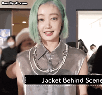 a girl with green hair is wearing a jacket behind the scene