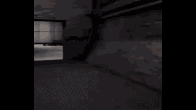 a person is laying on a bed in a dark room behind a glass door .