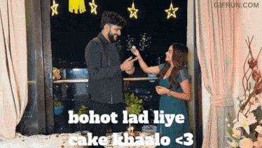 a man and a woman are standing in front of a window with the words bohot lad liye cake khailo < 3