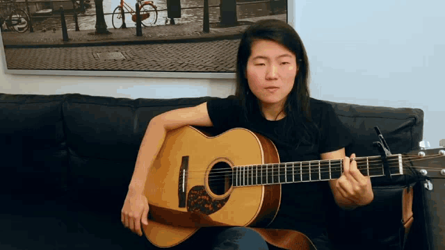 a woman sitting on a couch playing a guitar