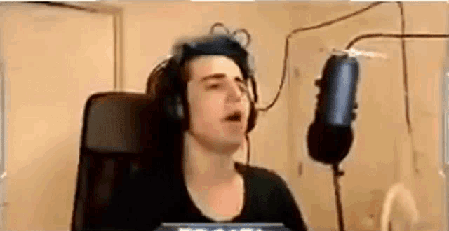 a man wearing headphones is singing into a microphone in a room .