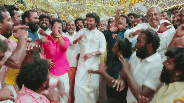 a man in a pink shirt is surrounded by a crowd of men
