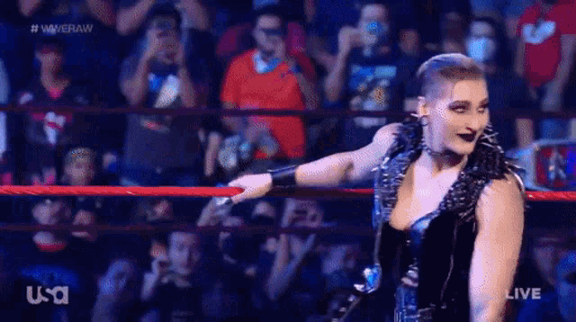 a woman is standing in a wrestling ring with a crowd behind her .