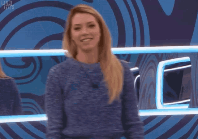 a woman in a blue sweater is smiling in front of a mirror with the words lulu gifs on it