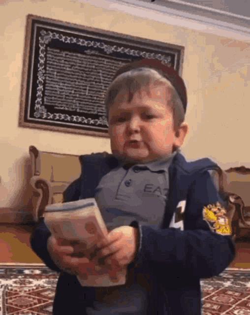 a little boy wearing a ea3 jacket is holding a book