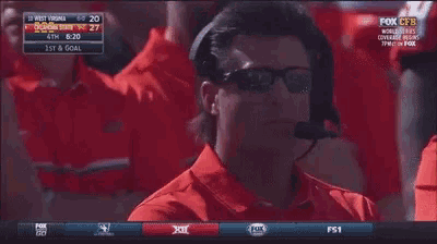 a man wearing sunglasses and a headset is watching a game on fox