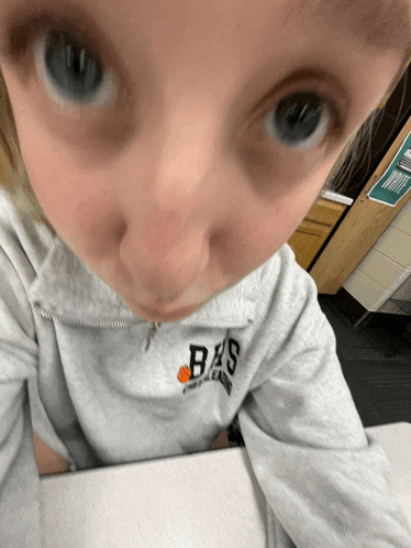 a person wearing a grey sweatshirt with the letter bs on the front