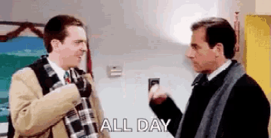 two men are standing next to each other in a room and one of them is holding a flashlight .