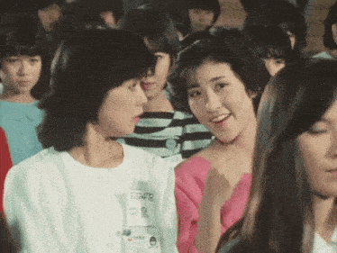 a group of young women are sitting in a room and one of them has a name tag that says sg48 on it .