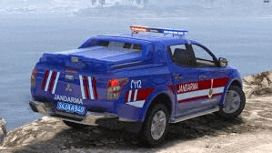 a blue jandarma truck is parked on the side of a road near the ocean .