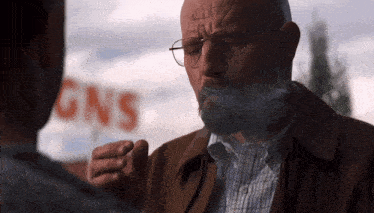 a man smoking a cigarette in front of a sign that says " gns "