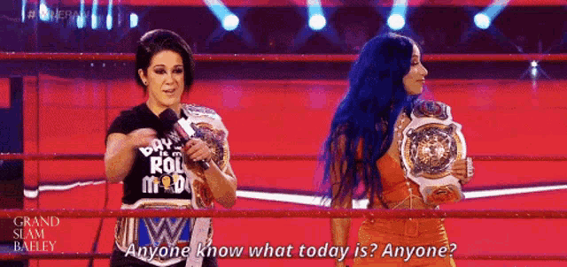 two women in a wrestling ring with one holding a microphone and the other holding a championship belt