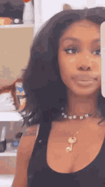 a woman wearing a necklace with a key on it is taking a selfie with her cell phone .