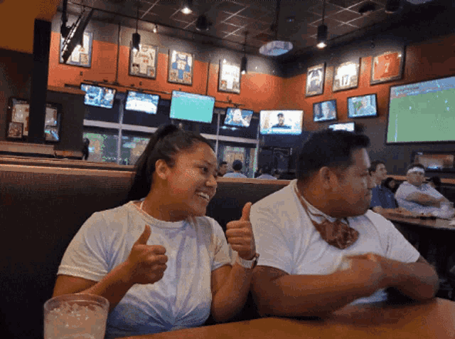 a man and a woman giving a thumbs up in a restaurant